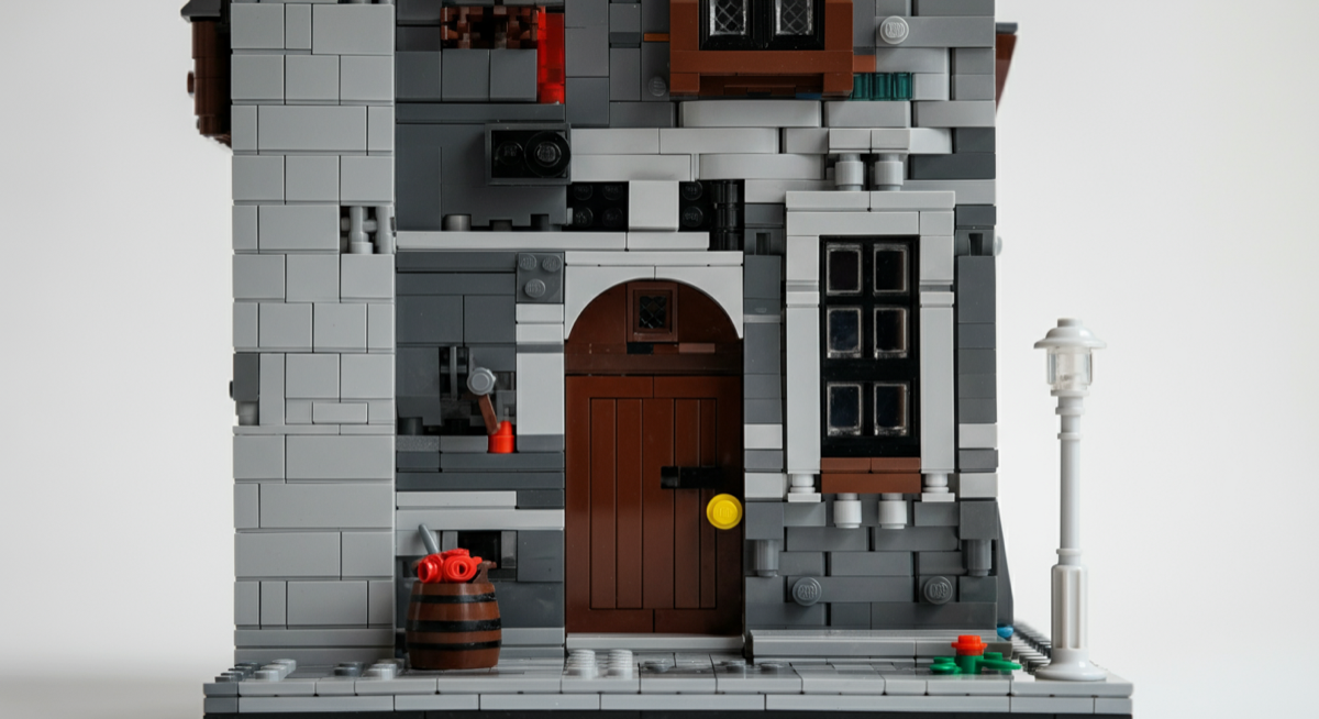 A brick-built building facade with a recessed arched door, framed window and sideways-built stone details
